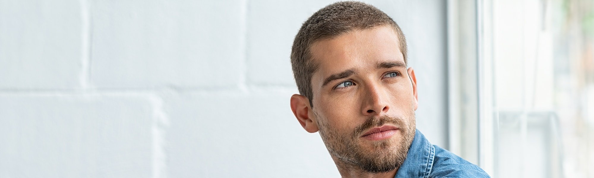 Ein junger Mann mit Kurzhaarfrisur schaut nachdenklich